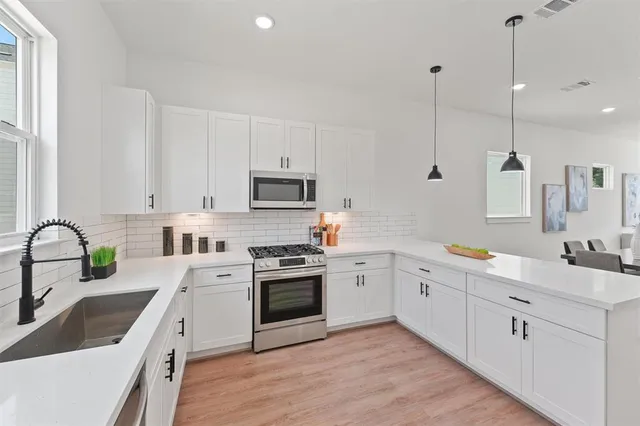 a kitchen with white cabinets appliances and sink