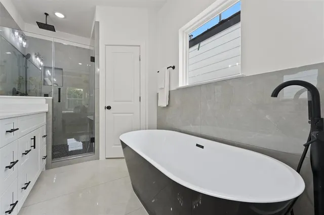 a bathroom with a tub a sink and a large mirror