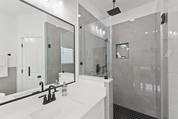 a bathroom with a tub shower sink and mirror