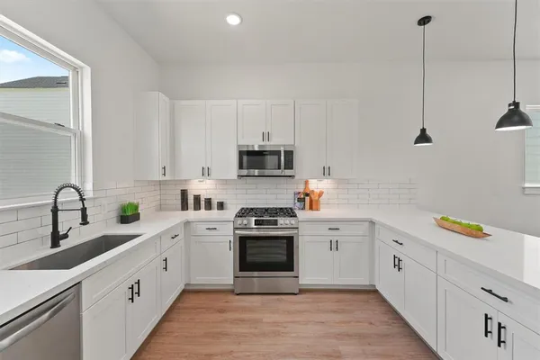 a kitchen with white cabinets appliances and a sink