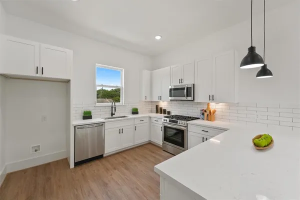a kitchen with sink a stove and chairs with wooden floor