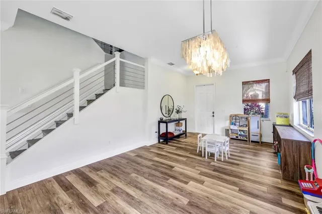 a dining room with wooden floor a chandelier a wooden table and chairs