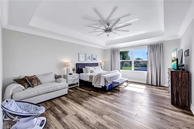 a spacious bedroom with a bed a couch and a potted plant with wooden floor