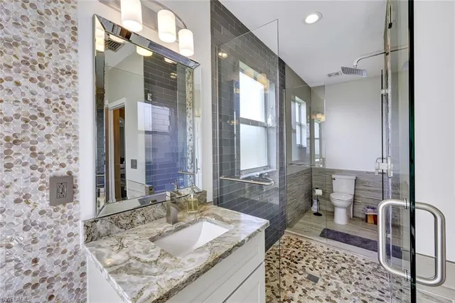 a bathroom with a granite countertop sink a toilet and shower