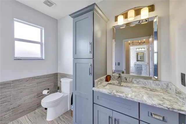 a bathroom with a granite countertop sink toilet and mirror