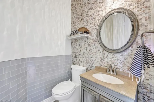 a bathroom with a granite countertop toilet a sink and a mirror