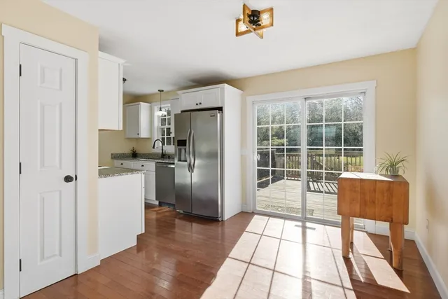 a kitchen with a refrigerator a stove and a dining table with wooden floor