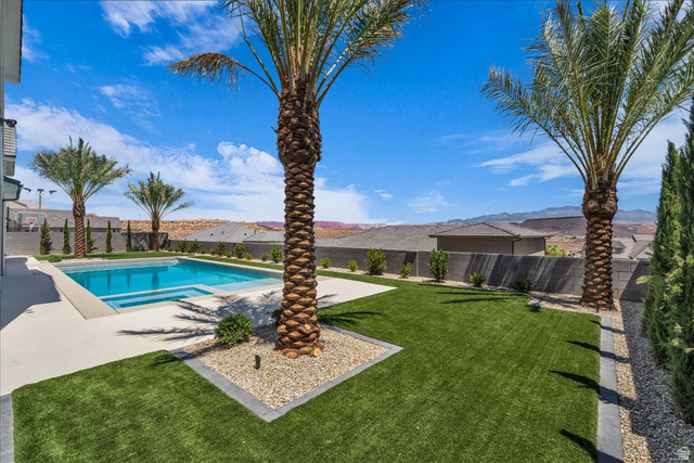 1620 Belayer Drive St. George, UT 84770 - Photo 40 of 51 Expansive backyard featuring a rectangular swimming pool with integrated spa, concrete decking, artificial turf, and mature palm trees
