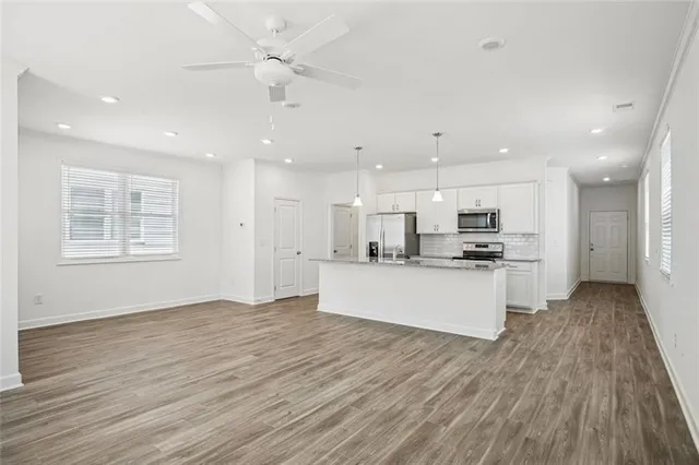 a kitchen with stainless steel appliances kitchen island wooden floor a refrigerator and a sink
