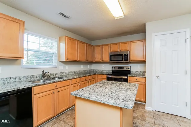 a kitchen with stainless steel appliances granite countertop a stove sink and microwave