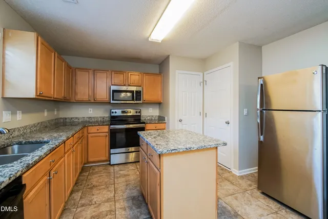 a kitchen with granite countertop a refrigerator stove top oven and sink