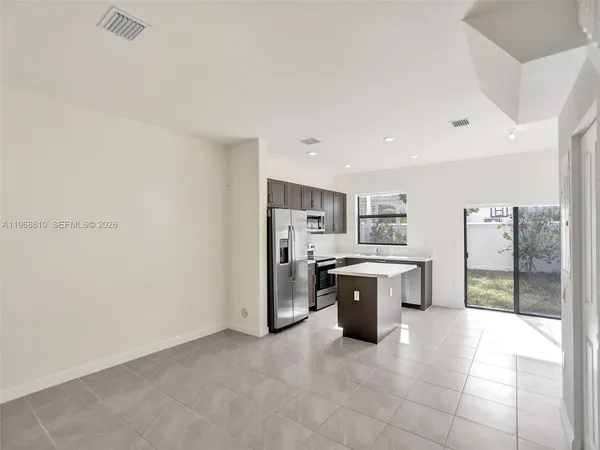 a large white kitchen with a refrigerator a stove top oven and a sink