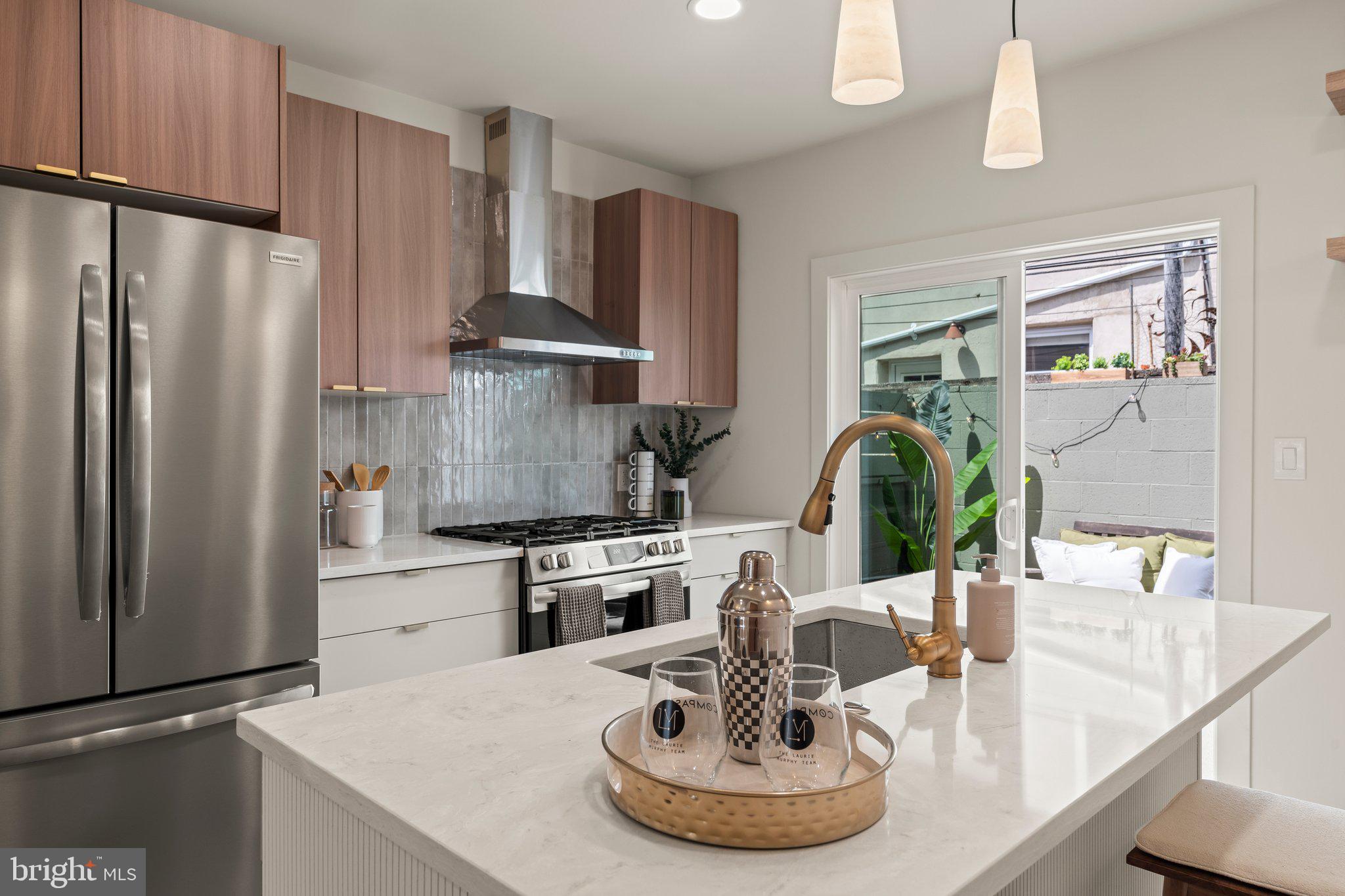 1031 Mercy Street Philadelphia, PA 19148 - Photo 14 of 34 a kitchen with stainless steel appliances kitchen island granite countertop a refrigerator a stove and a sink with wooden floor