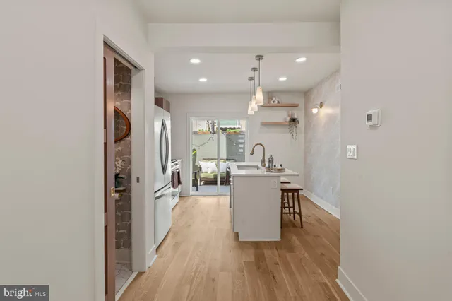 a living room with stainless steel appliances furniture a window and wooden floor