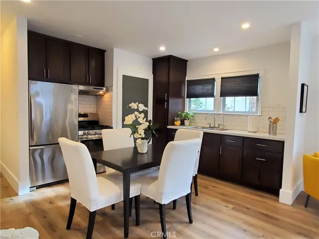 a kitchen with stainless steel appliances a dining table chairs refrigerator and sink