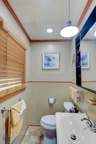 a bathroom with a sink a mirror a toilet and a window