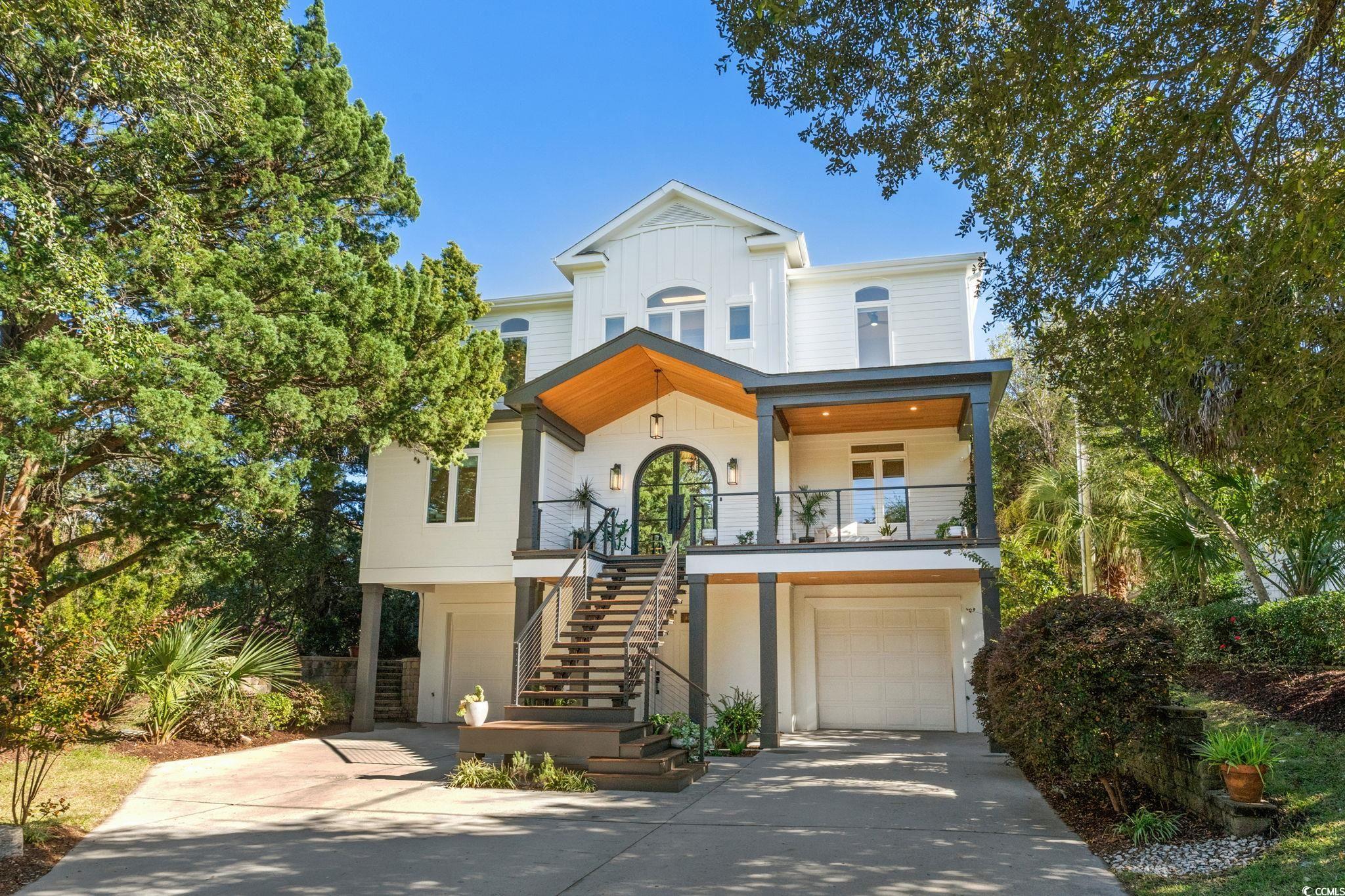 View of front of house featuring concrete driveway, a garage, stairs, and french doors