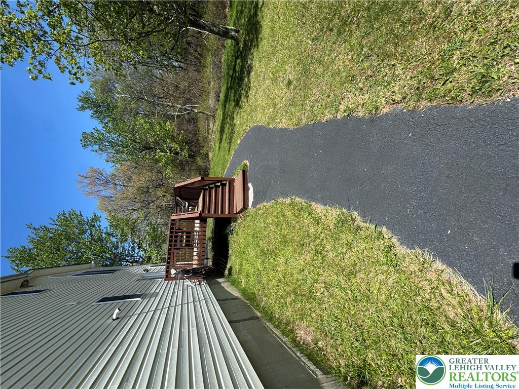 2742 Long Pond Road Long Pond, PA 18334 - Photo 12 of 57 A well-maintained paved path winds through lush green grass, leading to an elevated wooden deck.