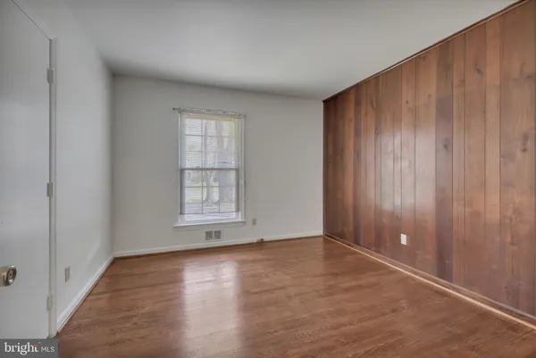 an empty room with wooden floor & closet and windows
