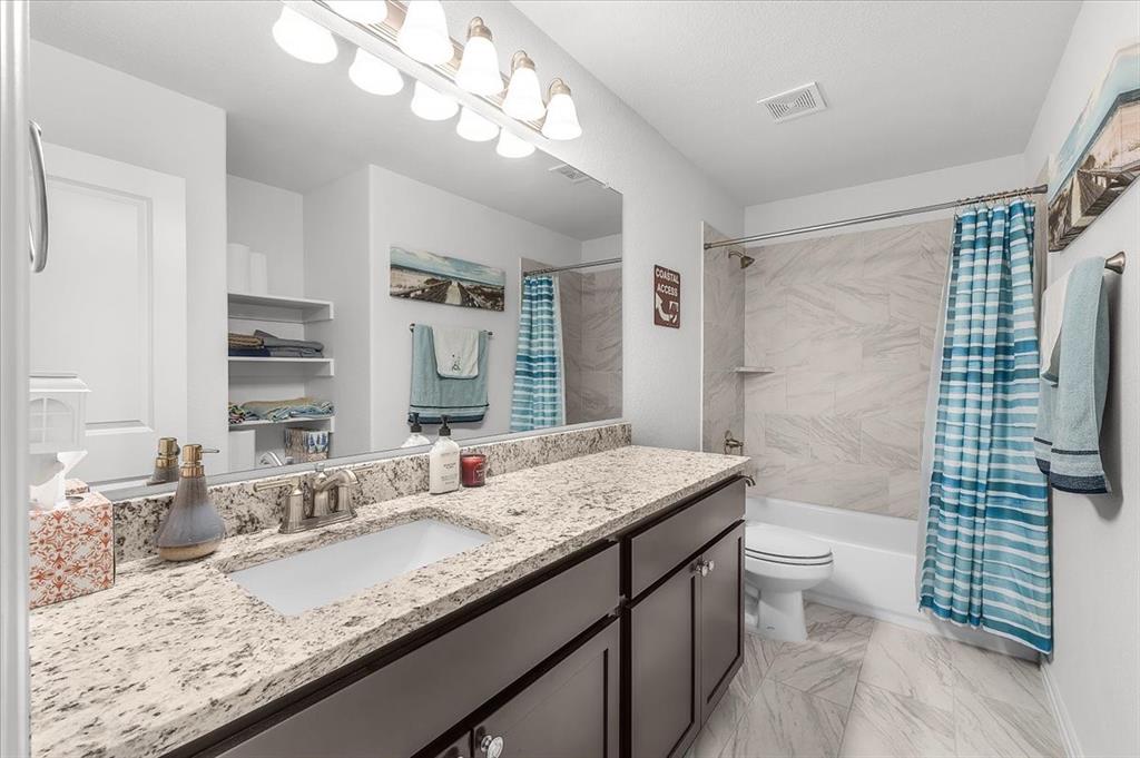 3797 Pine Road Poolville, TX 76487 - Photo 15 of 22 a bathroom with a granite countertop sink a toilet a mirror a vanity and shower