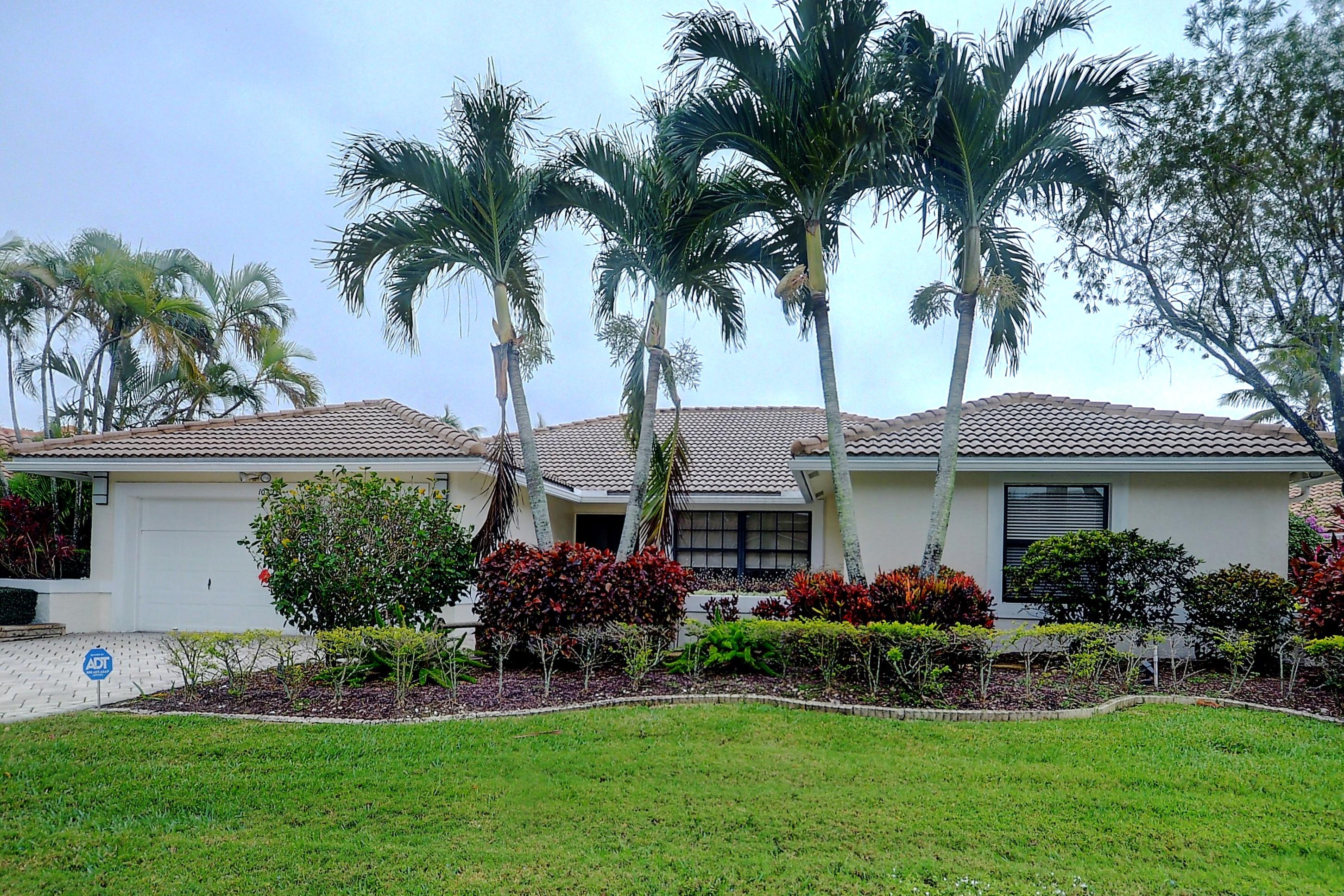 a front view of a house with a garden and palm trees