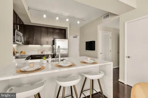 a kitchen with stainless steel appliances kitchen island granite countertop a table chairs and a refrigerator