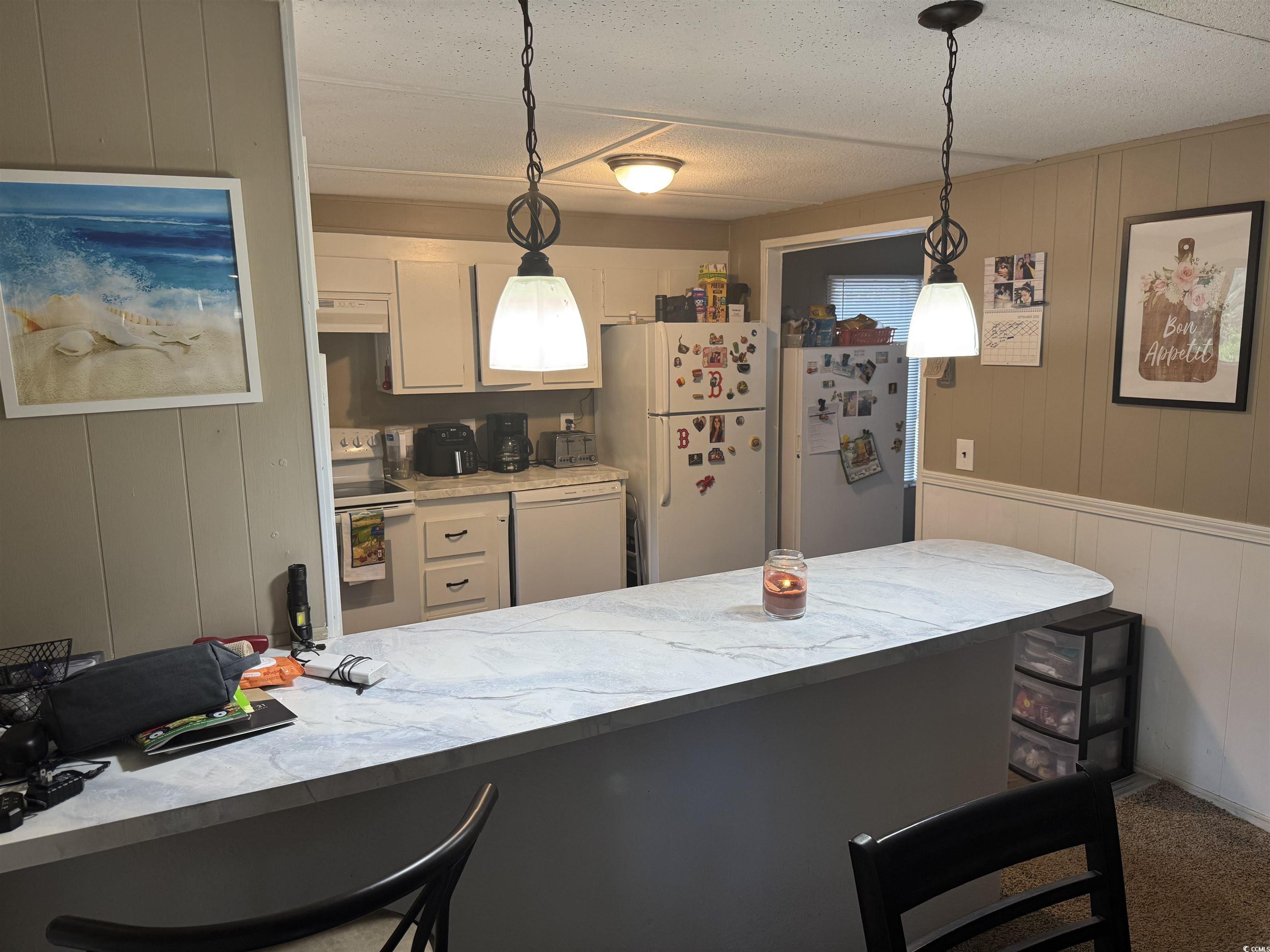 500 Palmetto Street Conway, SC 29527 - Photo 4 of 17 Kitchen with wooden walls, a breakfast bar area, light countertops, white appliances, and hanging light fixtures