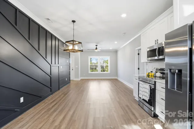 a kitchen with stainless steel appliances granite countertop a refrigerator a stove top oven a sink dishwasher and wooden cabinets with wooden floor