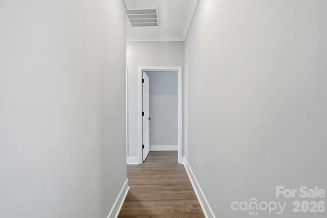 a view of a hallway with wooden floor and a bathroom
