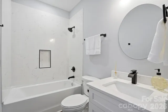 a bathroom with a granite countertop sink a toilet and bathtub