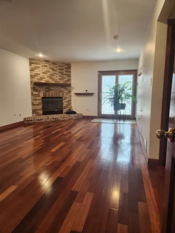 an empty room with wooden floor fireplace and windows