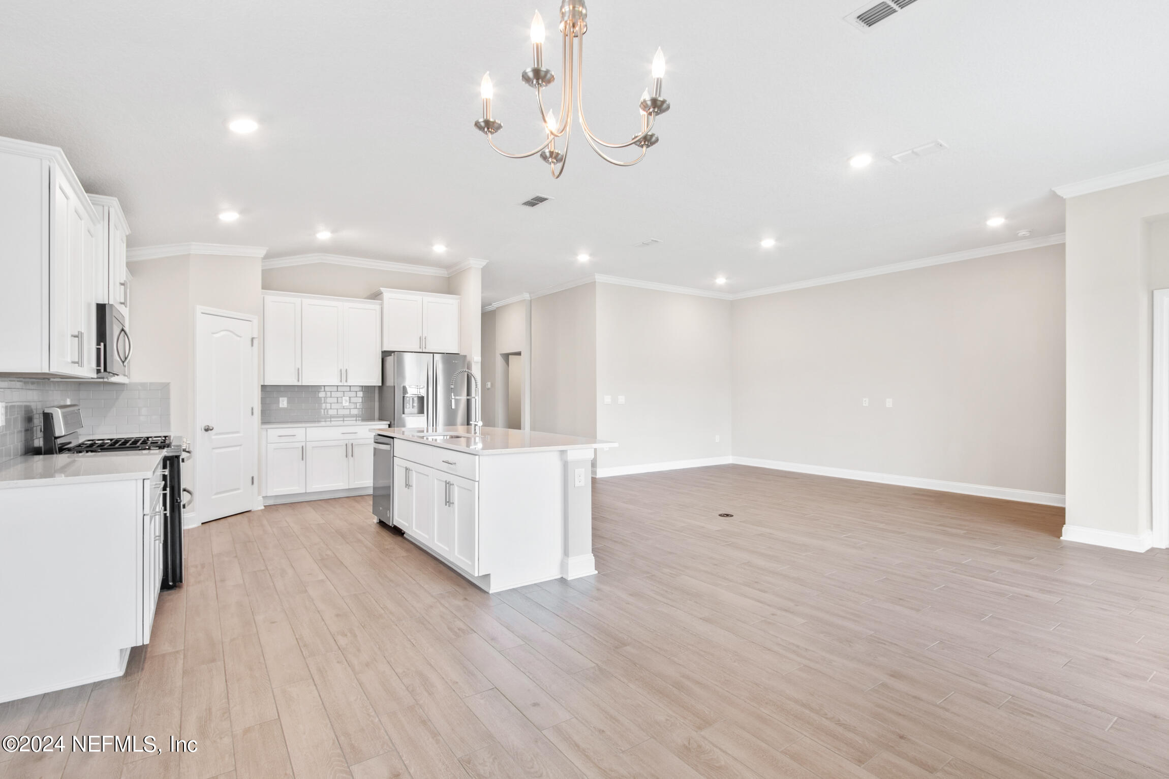 254 Ebro Road St. Augustine, FL 32084 - Photo 12 of 49 a large white kitchen with kitchen island a sink a center island stainless steel appliances and a cabinets
