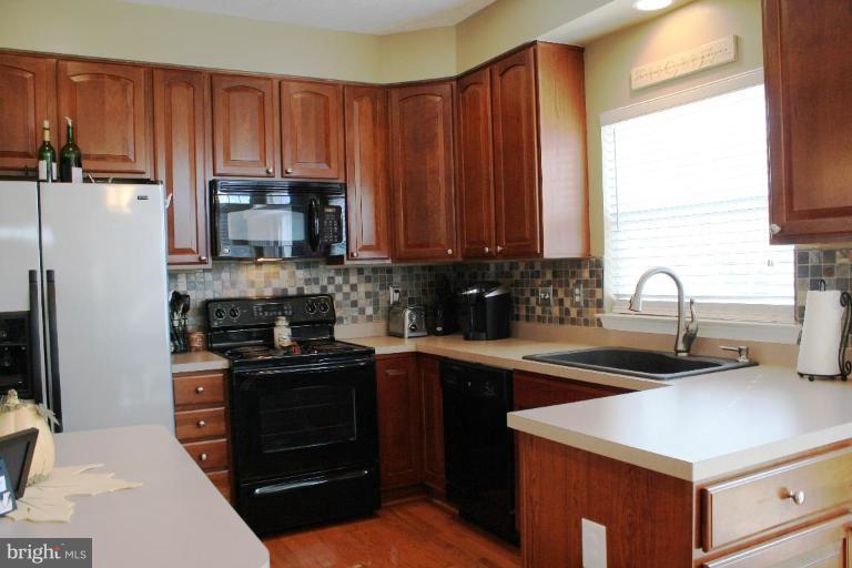 5627 New Forge Road White Marsh, MD 21162 - Photo 5 of 30 a kitchen with stainless steel appliances a sink a stove a refrigerator cabinets and a window