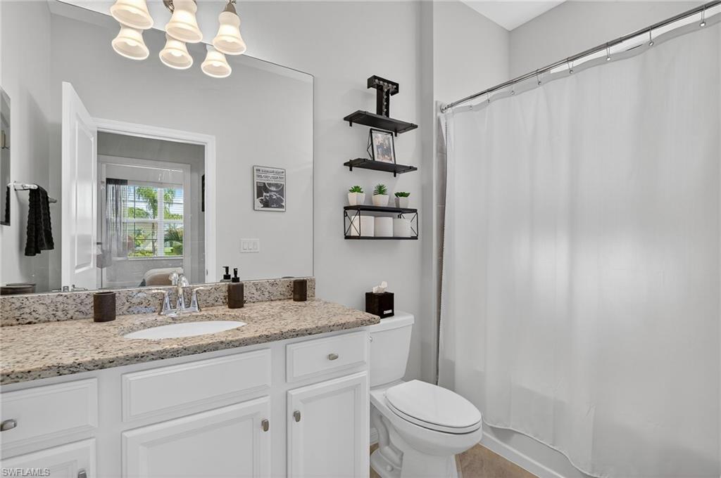 2130 Hamlin Street Naples, FL 34120 - Photo 20 of 43 a bathroom with a granite countertop sink a toilet and a mirror