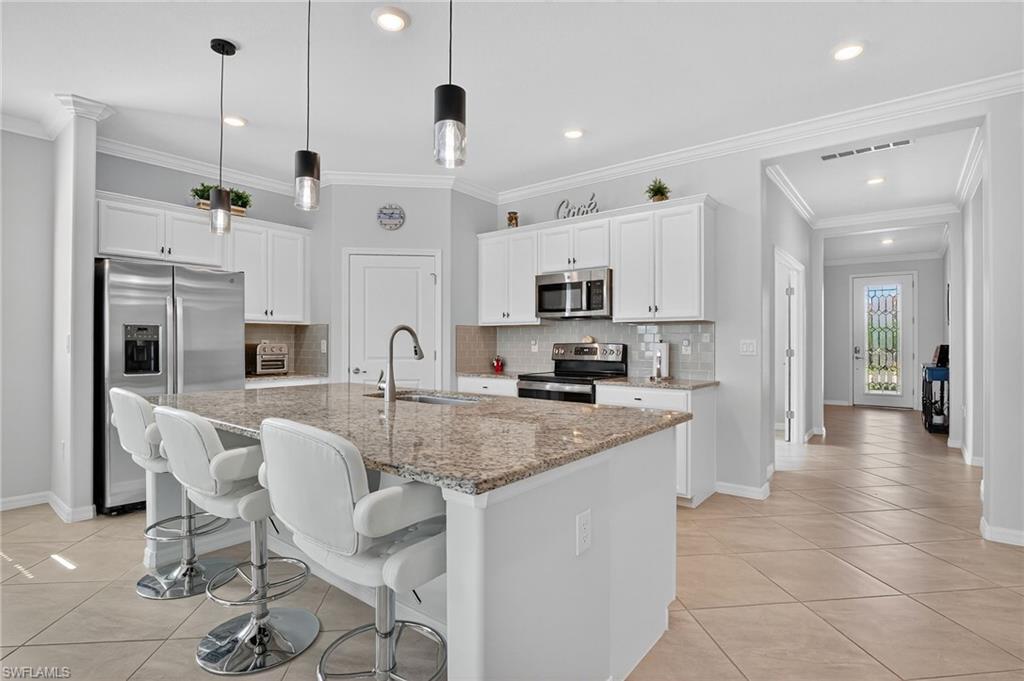 2130 Hamlin Street Naples, FL 34120 - Photo 3 of 43 a large kitchen with white cabinets and stainless steel appliances