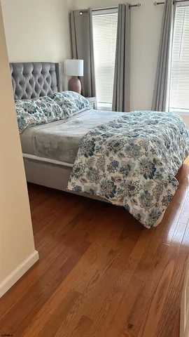 a bedroom with a bed wooden floor and a large window