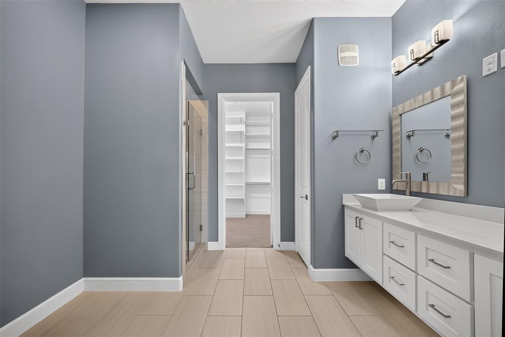 5015 Meridian Lane, Unit 2102 Addison, TX 75001 - Photo 21 of 36 Spacious bathroom featuring light-toned tile flooring, a glass-enclosed shower, and a white floating vanity with a vessel sink