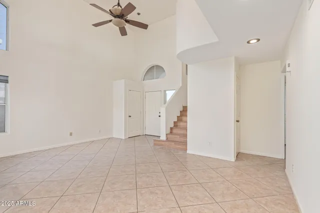 a view of a livingroom with a fireplace a ceiling fan and windows