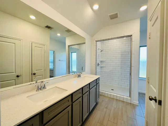 a bathroom with a sink double vanity granite tub shower and a mirror