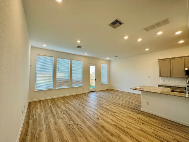 a view of an empty room with window and wooden floor