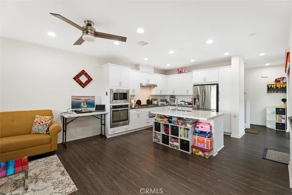 a living room with stainless steel appliances furniture and a view of kitchen