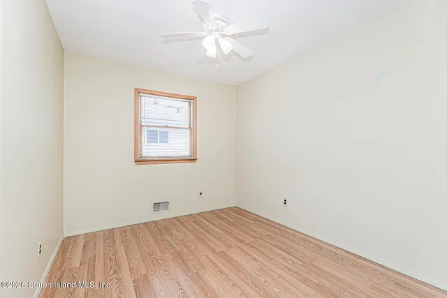 an empty room with a window and a ceiling fan