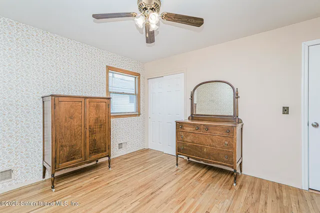 an empty room with wooden floor closet and windows