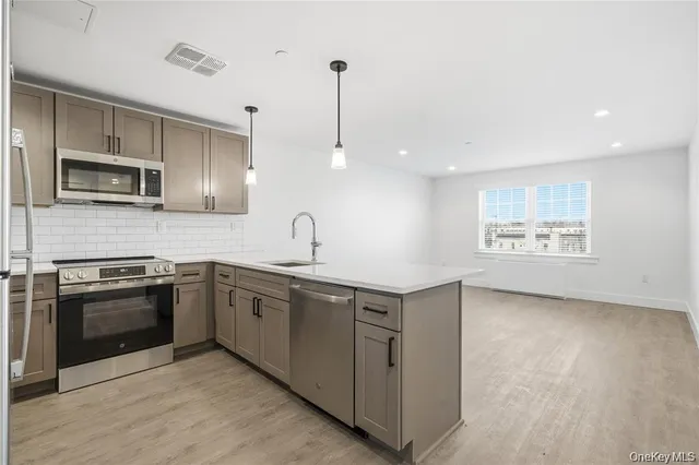 a kitchen with stainless steel appliances granite countertop a sink a stove a microwave and wooden floor