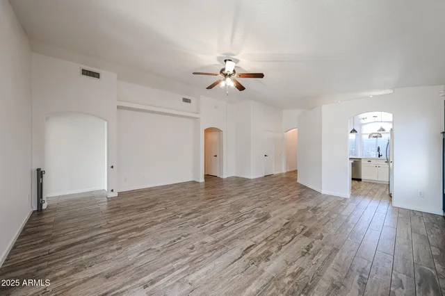 a view of an empty room with a window and wooden floor