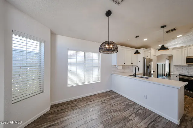 a kitchen with stainless steel appliances granite countertop a sink a stove and a wooden floors