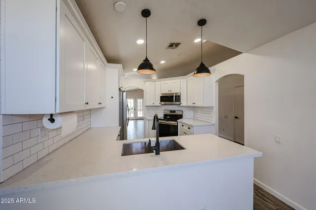 a kitchen with stainless steel appliances granite countertop a sink a stove and a refrigerator
