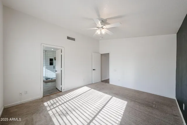 a bedroom with a large bed and a chandelier fan