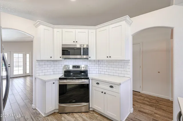 a kitchen with granite countertop white cabinets stainless steel appliances and a counter space