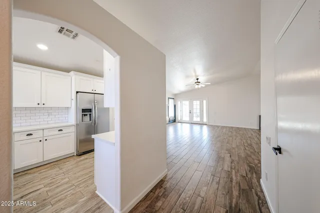 a view of empty room with wooden floor and fan